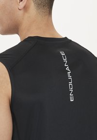 Sort ærmeløs træningsshirt med en glat tekstur; har "ENDURANCE" trykt lodret i hvidt på ryggen.