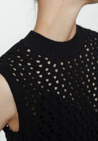 Schwarzes gestricktes ärmelloses Oberteil mit hohem, rundem Ausschnitt, das ein durchbrochenes Muster und gerippte Details entlang der Kanten aufweist.