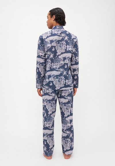 Tengerés pajama szett, részletes fehér dzsungelmintával, hosszú ujjakkal és laza szabású nadrággal. Az anyag sima, laza szabással.