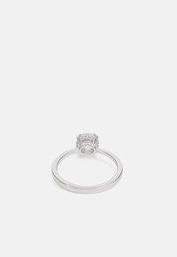 Bague en argent avec une pierre claire ressemblant à un diamant, sertie dans une griffe decorative, avec un bandeau lisse et fin.