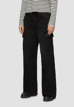 Pantalons cargo noirs à jambe large en denim, dotés de poches latérales et d'une finition texturée, associés à un haut à rayures à manches longues.