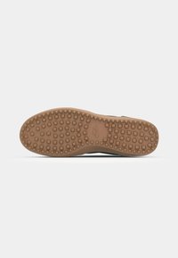 Nike shoe sole with a textured brown rubber base featuring small square patterns. The outsole is designed for traction and durability.