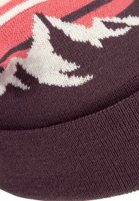 Strickmütze mit einem kastanienroten Bund, pink-weißer Bergmusterung und einer strukturierten Oberfläche. Die Farben sind kräftig und kontrastreich.