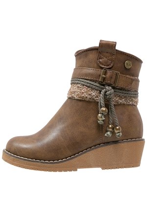 Bottine à talon compensé marron avec semelle texturée, bride décorative à boucle, bande tricotée et pompons en corde ornés de perles métalliques.