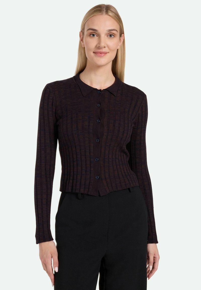 Cardigan de punto acanalado oscuro con cuello tipo solapa, que presenta una fila de botones azules y una silueta ajustada, combinado con pantalones negros.