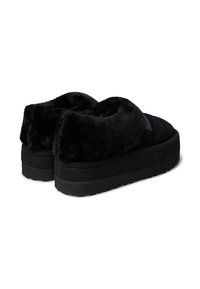 Pantofole nere con piattaforma, in morbido tessuto in pelliccia sintetica e suola in gomma. Punta arrotondata, colletto imbottito e sottile branding laterale.