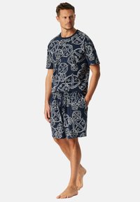 Ensemble de loungewear en coton marine comprenant un t-shirt et un short avec un motif de globes et d'étoiles blanches. Coupe décontractée avec une taille élastique.