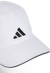 Biely šilt s čiernym logom Adidas, vyrobený z hladkej látky. Obsahuje zakrivený okraj a kontrastné šitie pozdĺž okrajov.