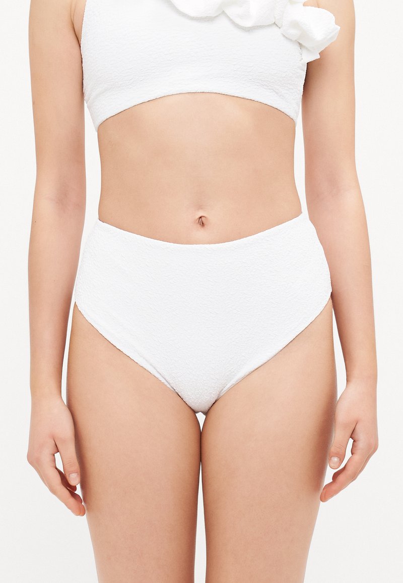 Biely bikiny set s textúrovanou látkou, vysokým pásom a skráteným topom s volánovým detailom na jednej strane.