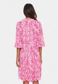 Rosa och vit mönstrad klänning med korta ärmar, utsvängd nederdel och texturerad tyg, med en lös passform och rund halsringning.