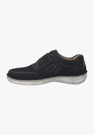 Scarpa slip-on in suede nero con cuciture grigie, suola in gomma e un pannello posteriore testurizzato. Presenta una cinghia con chiusura a velcro per una vestibilità sicura.