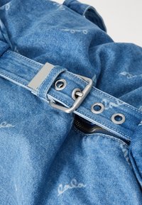 Τσάντα από μπλε τζιν υλικό με ασημί αξεσουάρ, λεπτομέρεια πόρπης ζώνης και φερμουάρ. Διαθέτει ραφές και μαλακή υφή.