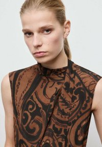 Brązowy top bez rękawów w wzory z wysokim kołnierzem i drapowanym fasonem. Posiada wirujące czarne nadruki na gładkim materiale.
