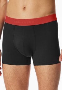 Sorte bomuldsboksershorts med en rød elastisk talje. Har en tætsiddende pasform, syningsdetaljer og en formet pouches for komfort.