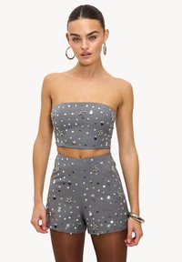 Ensemble gris deux pièces composé d'un crop top bustier et d'un short taille haute, orné de sequins circulaires argentés et de décorations.