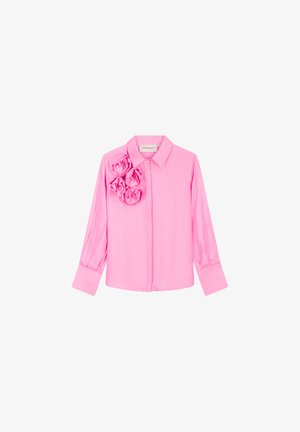 Pink blouse with long sleeves, button closure, and three floral fabric accents on the left side. Smooth texture, collar design.