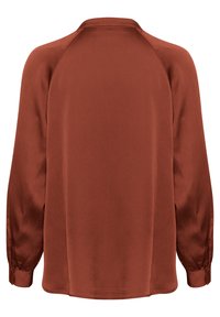 Blusa a maniche lunghe color ruggine con una texture liscia. Presenta un colletto rotondo e polsini arricciati. Orlo dritto nella parte inferiore.