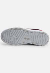 Gray rubber outsole with textured tread patterns. Embedded circular logo and brand name “FILA” printed on the side.