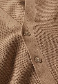 Hnědý pletený cardigan s texturovaným vzorem, předními knoflíky a tečkovanými detaily na měkké tkanině.