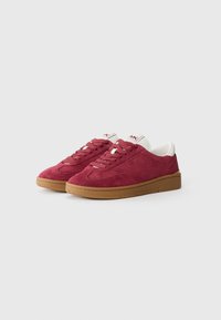Røde semskede sneakers med hvide detaljer og snørebånd, med en gummisål og rund tå-design. Mærkets logo på tungen.