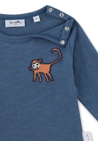 Blaues Babyshirt mit orangefarbener gestickter Affenapplikation auf der Brust und Druckknöpfen an der Schulter für ein einfaches Ankleiden.