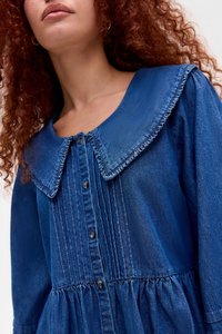 Τζιν φορεμα σε σκούρο μπλε χρώμα με μεγάλο φουσκωτό γιακά, τζάμι μπροστά και πλισέ λεπτομέρειες, διαθέτοντας συγκεντρωμένη μέση και απαλή υφή.