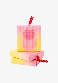 Opakowanie zestawu Biodance Glow Duo ma gradientowy wzór w kolorze różowym i żółtym z podniesioną teksturą w prążki; zawiera czerwoną wstążkę z logo.