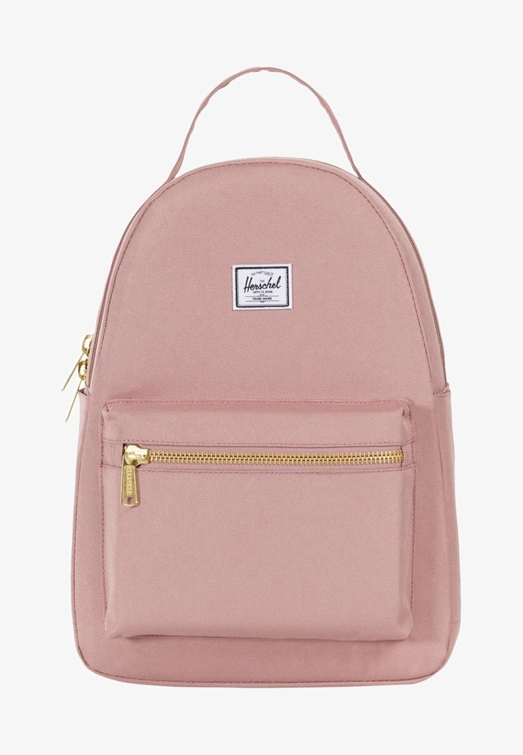 Jasnoróżowy plecak wykonany z płótna. O zaokrąglonym kształcie z przednią kieszenią na zamek. Posiada biały naszywkę z logo oraz złote elementy zamka.