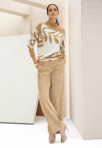 Beige trui met bladrand, lichtblauwe accenten; beige corduroy wijde broek; neutrale hoge hakken; parels als accessoires.