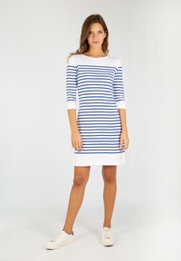 Abito a righe blu e bianche con maniche a tre quarti, scollatura rotonda e accentuazione dell'orlo anteriore; abbinato a sneakers bianche.