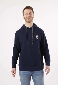 Haut à capuche bleu marine en mélange de coton, avec capuche à cordon de serrage, poche avant et patch logo. Texture douce avec des poignets et un ourlet côtelés.