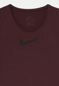 Camiseta atlética burdeos hecha de una tela que absorbe la humedad con un escote redondeado. Presenta un logo de Nike en negro en la parte frontal.