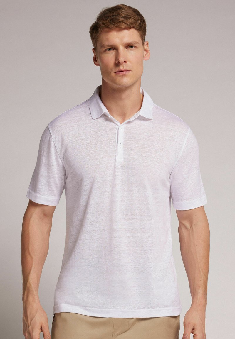 Bílá polo košile s krátkým rukávem vyrobená z lehké, texturované tkaniny, s klasickým límečkem a zapínáním na tři knoflíky.