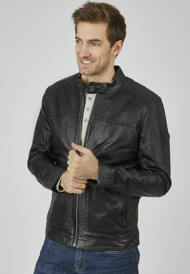 Schwarze Lederjacke mit hohem Kragen, Frontreißverschluss und kontrastierenden grauen Knöpfen. Verfügt über gestickte Details an Schultern und Manschetten.
