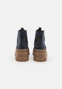 Zapatillas altas de navy con un upper texturizado, detalles en negro y una suela de goma marrón. Presentan una tira de agarre y un detalle de marca en el lateral.