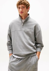 Grijze fleece sweatshirt met een kwartrits, geribbelde manchetten en geborduurd logo op de borst. Gecombineerd met bijpassende grijze broek.
