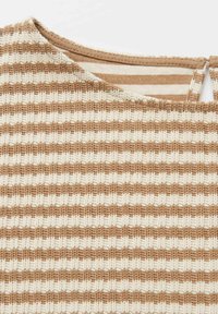 Vêtement tricoté à rayures horizontales beige et blanc, avec un col rond et une fermeture par bouton et boucle au dos.