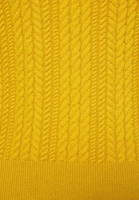 Tejido de punto amarillo con un patrón de cable texturizado. El diseño incluye puntos en relieve entrelazados, con un dobladillo acanalado en la parte inferior.