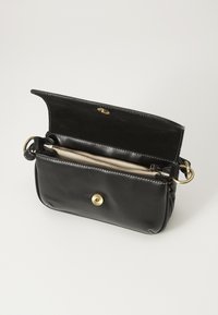 Borsa a tracolla in pelle nera con un compartimento con zip, chiusura a scatto magnetico e hardware color oro. Gli interni presentano una fodera testurizzata.