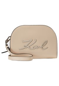 Beige läder crossover-väska med en mjuk textur, med en silverfärgad "Karl"-logotyp och en tunn rem med svarta accenter.