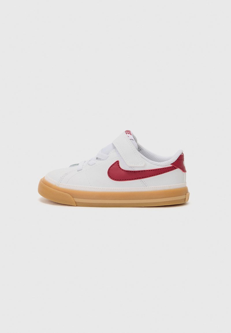 Fehér sneaker piros kiemelésű logóval, amely tépőzáras pánttal, kerek orral és gumis talppal rendelkezik a tapadás és rugalmasság érdekében.