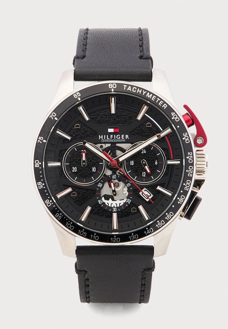 Ρολόι χρονογράφος Tommy Hilfiger με μαύρο καντράν, στεφάνη ταχυμέτρου, τρεις υποκαντράν, κόκκινο δευτερόλεπτο δείκτη και μαύρο δερμάτινο λουράκι.