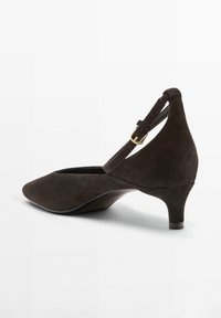 Brown suede pump with a pointed toe, ankle strap, and a small wedge heel. Features a gold-tone buckle accent.