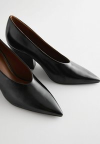 Svarta läderhögklackade pumps med spetsig tå, med en slät yta och en medelhög blockklack för stabilitet.