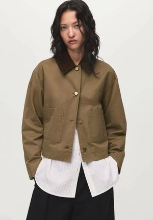 Khaki cropped jacket with a corduroy collar, two front pockets, button closure, and a smooth cotton texture, layered over a white striped shirt.