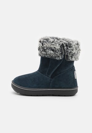 Botte d'hiver bleu marine pour enfant avec parement en fausse fourrure grise et semelle noire, vue de profil sur fond blanc.