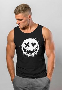 Black tank top featuring a large white graphic of a smiling face with teeth, accented by dripping paint and a heart and cross design.