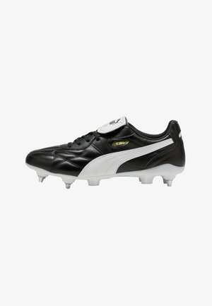 Scarpa da calcio in pelle nera con logo Puma bianco, tacchetti metallici e linguetta pieghevole con marchio Puma su sfondo bianco.