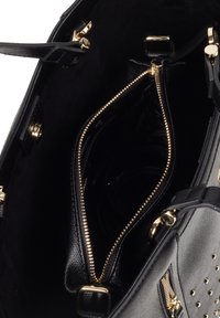 Wnętrze czarnej skórzanej torebki z zamykanymi na zamek przegródkami, złotymi akcentami i teksturowanym wykończeniem. Otwiera się na przestronną, ciemną podszewkę.