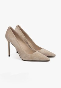 Beige suède hoge hakken met puntige neuzen en dunne stilettohakken. Kenmerkt zich door een gladde textuur en een minimalistisch ontwerp.